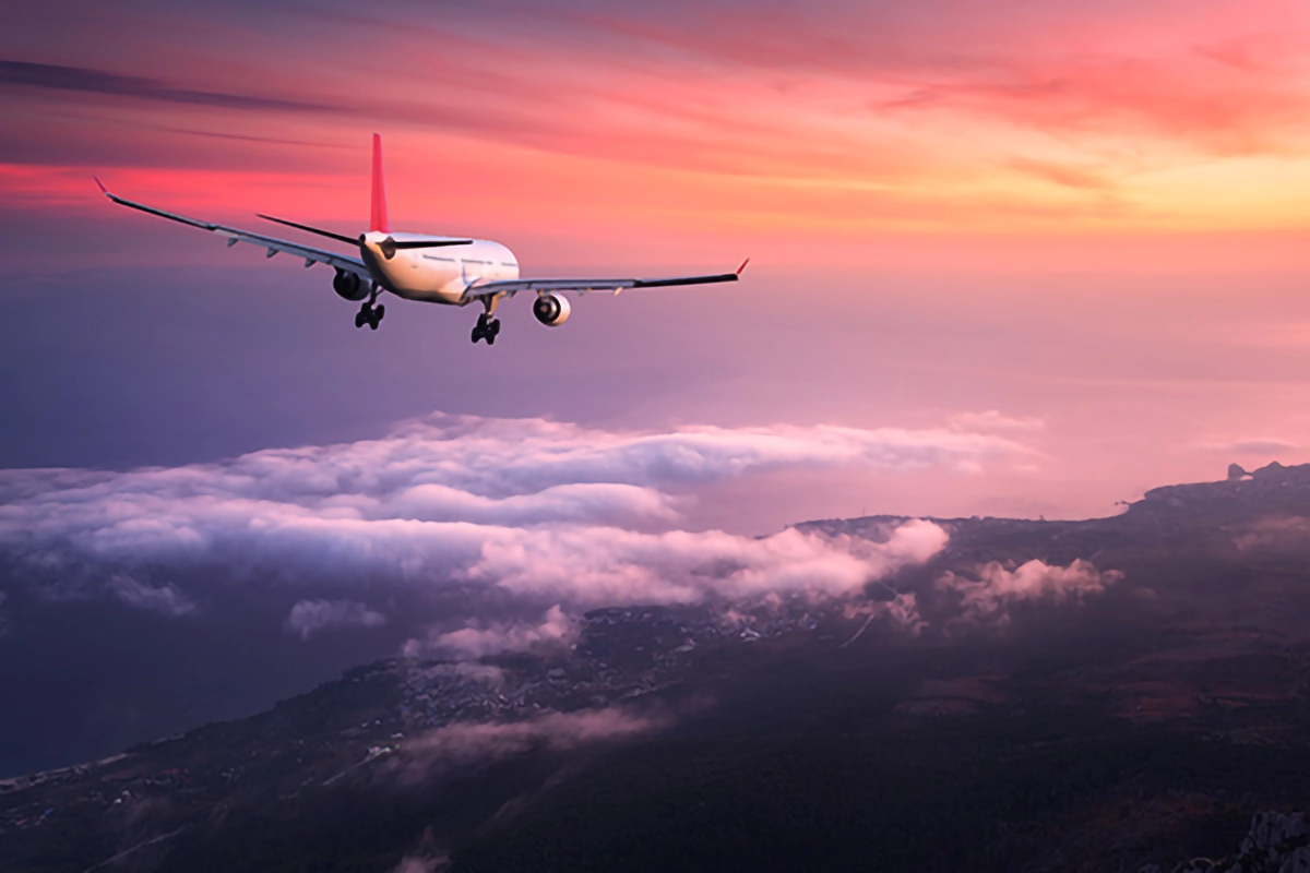 Image shows a plane landing in a red sunset